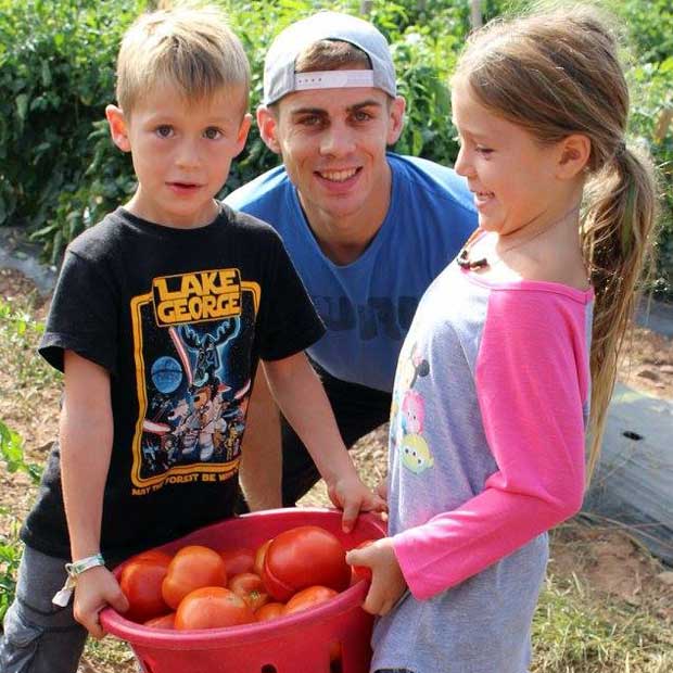 Photo courtesy of Simon M. Simon goes tomato picking with his host kids.