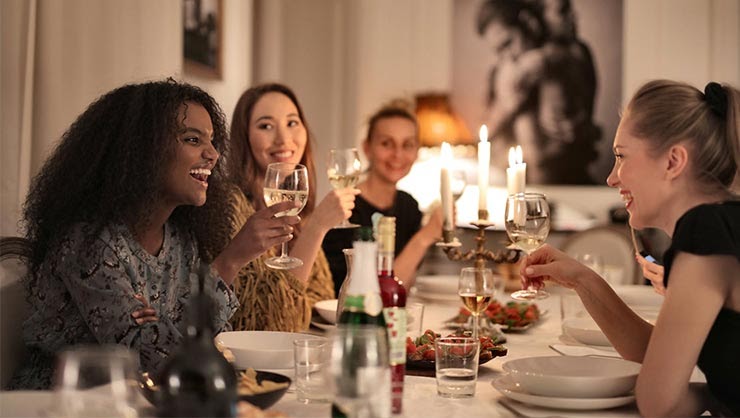 A smiling group of young women having dinner.