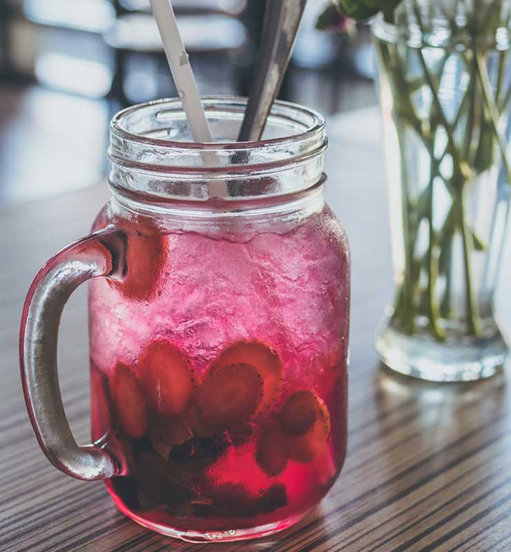 Jar of strawberry drink in mason jar with straw and spoon