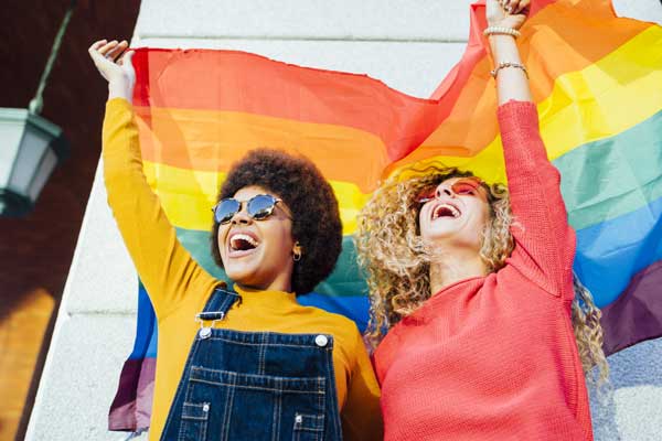 Smiling women holding a pride flag