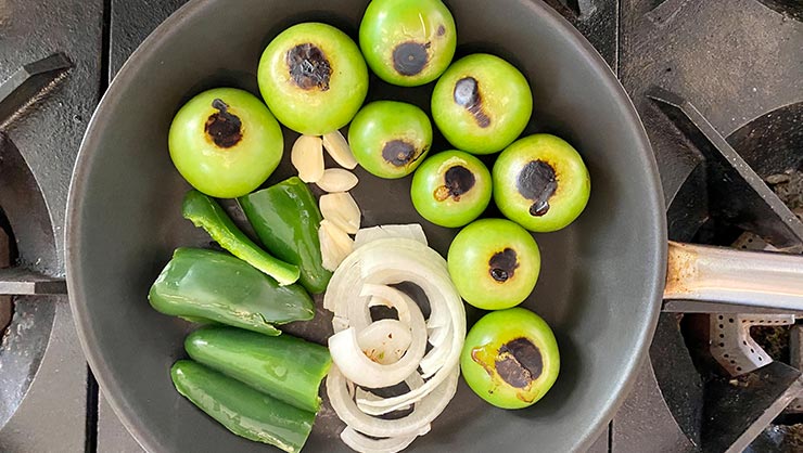 Tomatillos, onion, garlic, and jalapenos on a pan